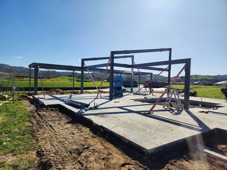 Steel portal frame structure erected on a concrete foundation during a construction project.