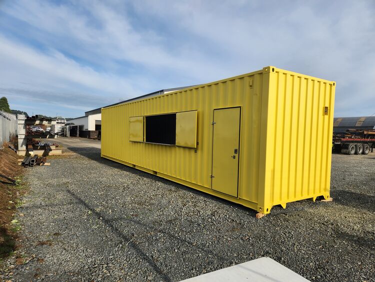 Yellow modified shipping container with access door and serving window manufactured for commercial or site use.