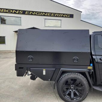 Heavy duty black steel canopy tray fitted to a utility vehicle for secure equipment and tool storage by Gibbons Engineering.