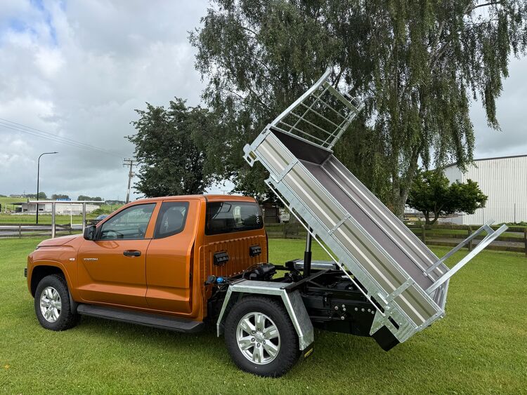 Hydraulic tipping ute tray installed on an orange pickup truck for transport and landscaping applications.